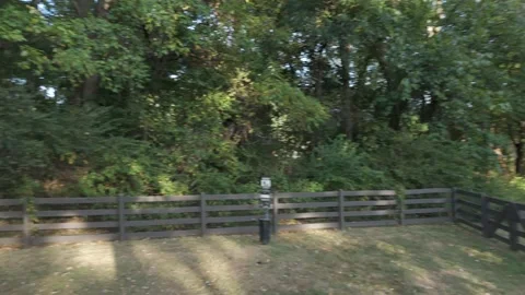 Slow motion drone flyover of park trees and fence line Stock Footage 346732685