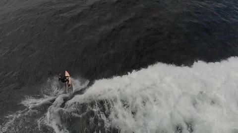 Slow motion drone footage of wave breaking as camera pans to surfer carving wave Video stock 96235974