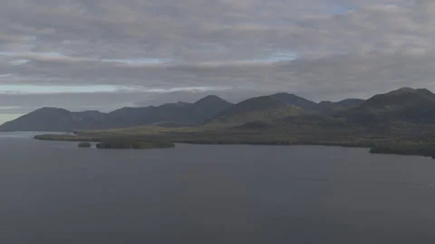 Slow Motion Drone Lake with Pine Tree Mountains in Background and Boats Passing Stock Footage 255319245