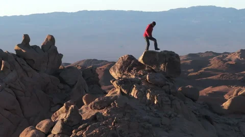 Slow motion drone shot of alone hiker man climbing on mountain peak Video stock 308773945