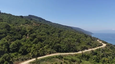 Slow Motion Drone View of Winding Dirt Road Along Green Coastal Mountain Stock Footage 341530630
