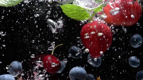 Slow motion drop of blueberries and strawberries into water on black background Stock Footage 156470179