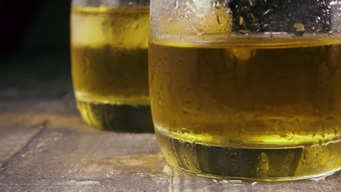 Slow motion drops and ice cubes in a glass with an alcoholic drink Stock-Footage 94032692