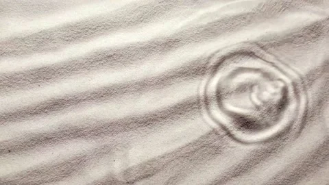 Slow motion of drops cascading down onto sandy surface, creating tranquil r.. Stock Footage 330987434