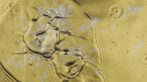 Slow motion. Drops of liquid silver paint fall down onto the gold paint. Splash 库存影片 163200417