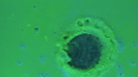Slow motion. Drops of paint fall into green fluorescent paint. 库存影片 133713224