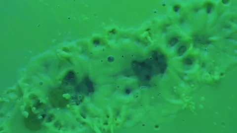 Slow motion. Drops of paint fall into green fluorescent paint. 库存影片 133713488