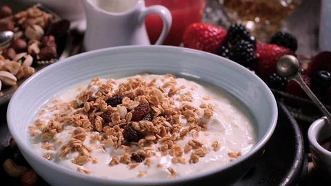 Slow motion: dry fruits falling over o bowl of yogurt with cereals and berries Stock Footage 73145609