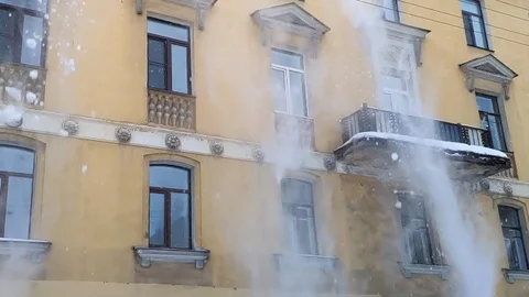 Slow motion dumping white snow from the roof of a building in old town Stock Footage 101398805