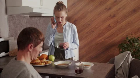 Slow motion. During breakfast, the husband watches the time on the phone, the Stock Footage 145052776