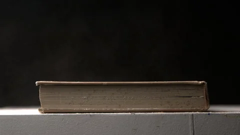 Slow Motion of Dust Blowing Off of a Closed Book on a Table Stock Footage 270398780