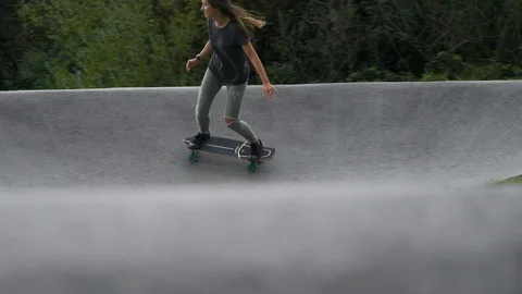 SLOW MOTION Dynamic shot of a young woman skateboarding in concrete skatepark Stock Footage 118930332
