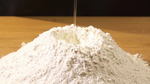 Slow motion. The egg is broken into sifted flour Stock Footage 76397869