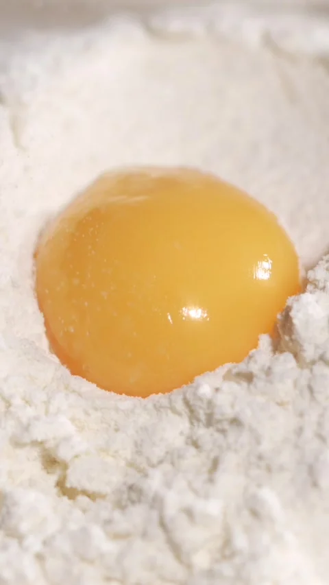Slow motion egg yolk breaking in flour Video stock 344986908