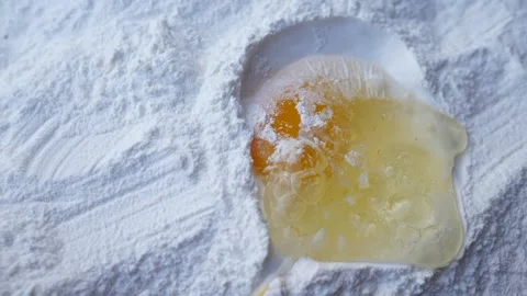 Slow motion of an egg yolk falling on a pile of flour Stock Footage 160555237