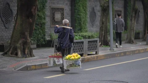 Slow motion of elderly fruit vendor walking with traditional baskets in Chengdu Stock Footage 315582951
