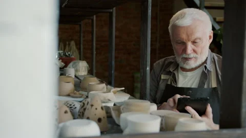 Slow motion of elderly man potter using tablet during inventory in workshop Stock Footage 141059512