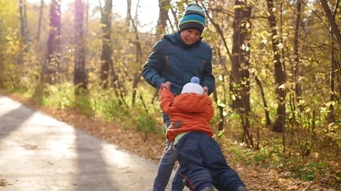 Slow motion. The eldest child whirling his laughing brother. Entertainment in Vidéo 80812054