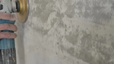 Slow motion of electric grinder sanding concrete wall with flying dust particles Stock-Footage 333326246