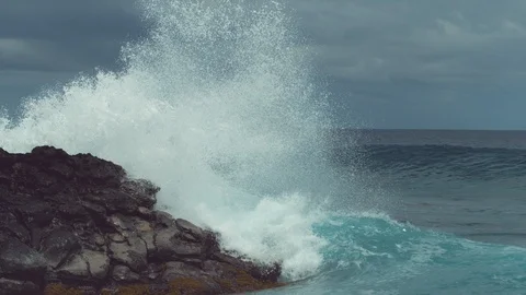SLOW MOTION: Emerald breaking wave hits the rocky coast with incredible force. Stock Footage 91231468