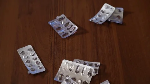Slow motion. Empty blister packs of pills on the table are stirred by hand Stock Footage 128840554