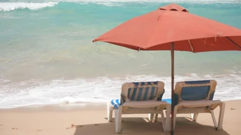Slow motion of empty sun loungers and parasol on the sandy beach near the sea 스톡 동영상 272783023