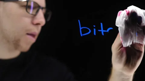 Slow motion erases the word bitcoin from the glass. A man in black clothes and Stock Footage 166159482