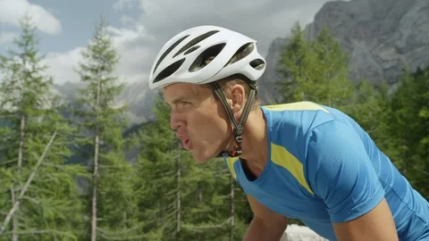 SLOW MOTION: Exhausted road cyclist bikes up a beautiful sunny mountain road. Stock Footage 86559201