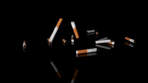 Slow-motion fall of cigarettes butts on black mirroring surface, studio-shot. Stock Footage 147527522