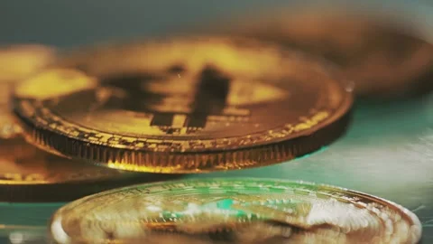 Slow motion fall of golden bitcoin physical coins on reflective green surface Stock Footage 337389833