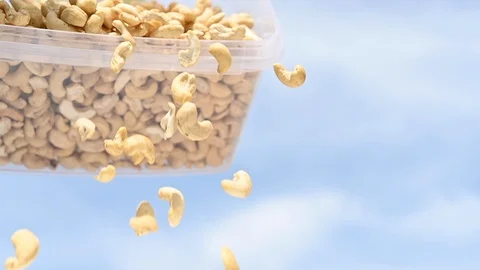 Slow motion falling cashews from plastic box sky background Stock Footage 107685942
