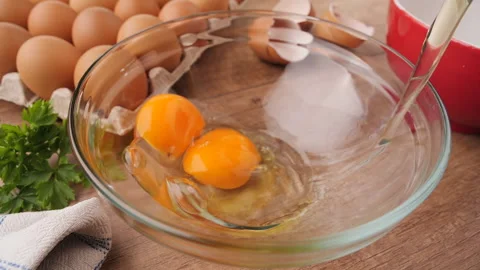 Slow motion of falling eggs into glass bowl - top view Video stock 181656814
