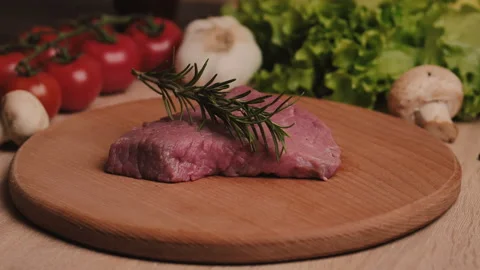 Slow motion of falling sprig of rosemary on fresh raw beef, veal steak Stock Footage 151121951