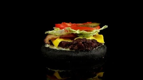 Slow motion of falling top bun, juicy black burger Stock Footage 77585911