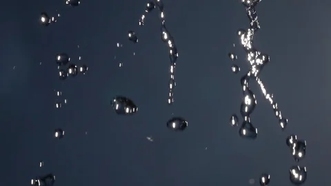Slow motion of falling water drops on blue sky backdrop with flying flies. Stock Footage 100237125