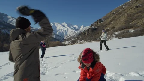 Slow motion of family standing far apart having snowball fight near mountain / Stock Footage 106945002
