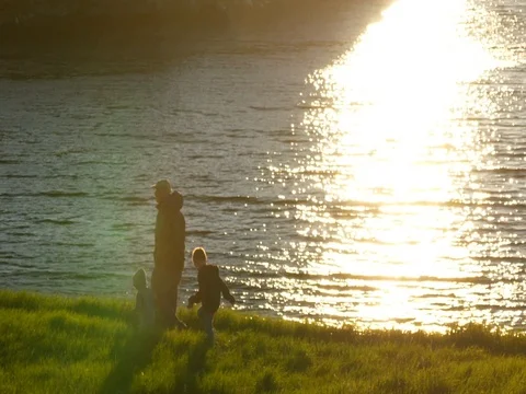 Slow motion of family walking along ocean at sunset Stock Footage