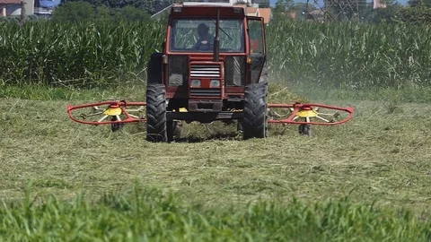 Slow motion farmer driving tedder Stock Footage 113570544