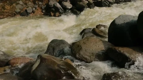 Slow motion of a fast flowing mountain river passing over large rocks Video stock 319921681