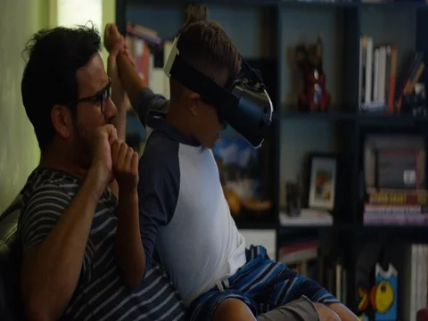 Slow Motion of father and son playing with Virtual Reality headset at home Stock Footage 78490904