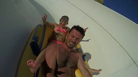 Slow motion, father going down on water slide with his young beautiful daughter Stock Footage 64977908