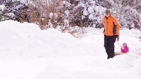 Slow motion father pulling faughter on her bobsled Stock-Footage 80128777