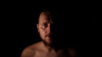 Slow motion - fighter man appears from the dark sweating and taking a rest  Stock Footage 85766591