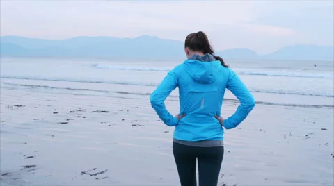 Slow motion of fit sporty woman walking towards shoreline on beach Stock Footage 59074002