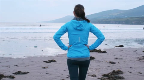 Slow motion of fit woman walking towards shoreline on beach Stock Footage 59081500