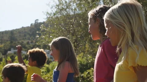 Slow motion of five children playing with bubbles in park. Video stock 43673299
