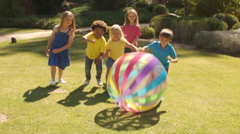 Slow motion of five children pushing beach ball towards camera in park. Stock Footage 43673111