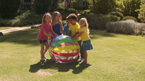 Slow motion of five children pushing beach ball towards camera in park. Stock Footage 43673117