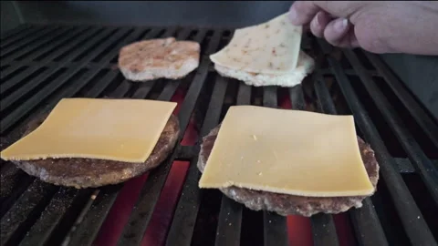 Slow motion flames and smoke beneath cheeseburgers and chicken burgers while Stockbeeldmateriaal 337182297