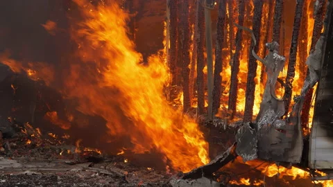 Slow motion flames burning a small building down to nothing. House wall being Stock Footage 232337550